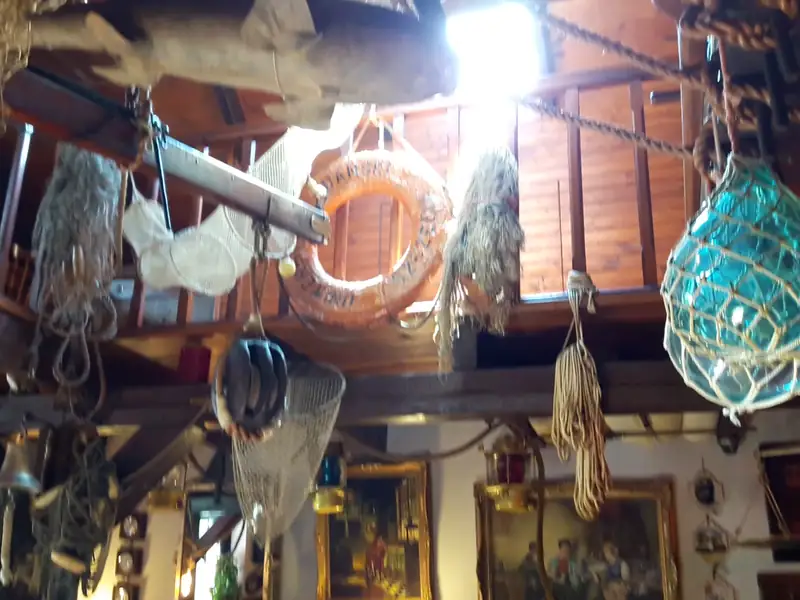 Sieci rybackie, bojki i lampy pod drewnianym stropem