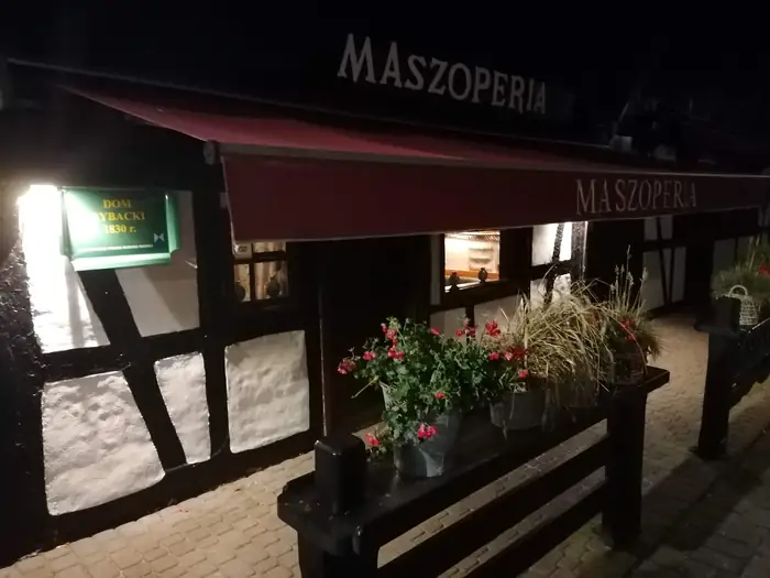 Zielona tabliczka Dom rybacki na fasadzie Maszoperii wieczorem
